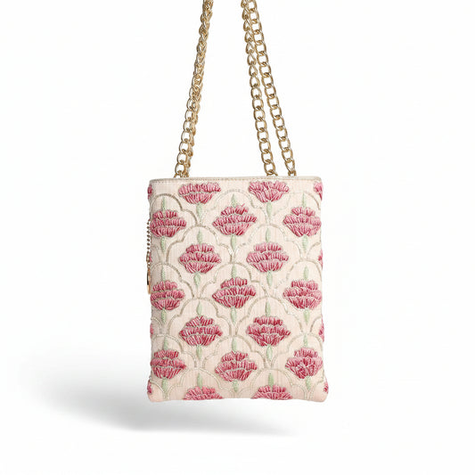 Woman holding a floral-patterned handbag with a gold chain strap on a light background