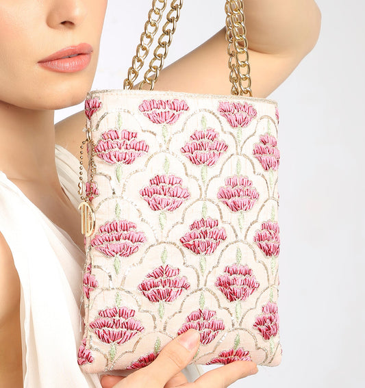 Woman holding a floral-patterned handbag with a gold chain strap on a light background
