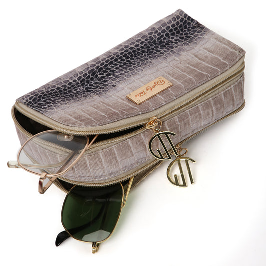 A beige jacquard sunglass cover with a crocodile pattern, zipper closure, and a brand tag on the top. It contains two pairs of sunglasses inside.