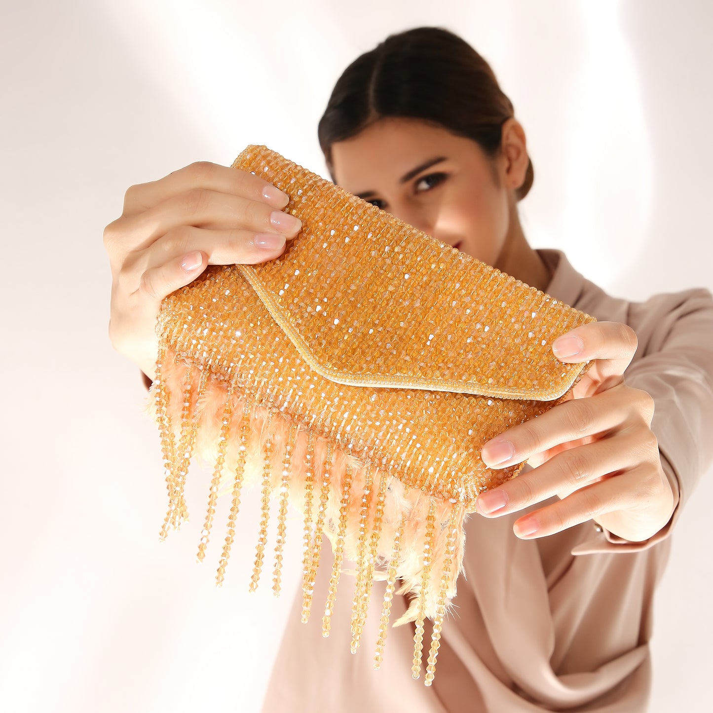 Woman holding a gold beaded clutch against a white background