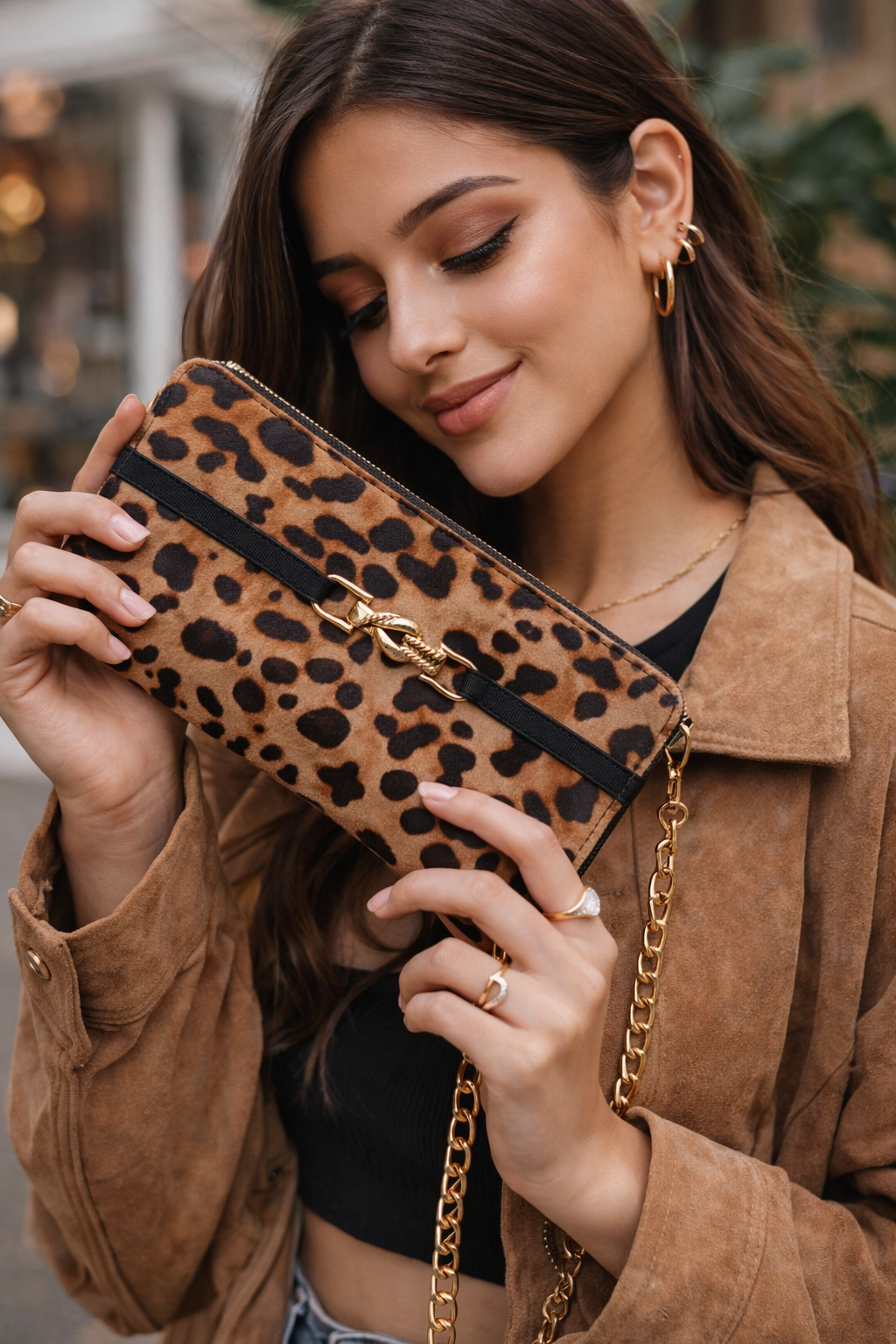 Woman holding a leopard print clutch with a gold chain strap.